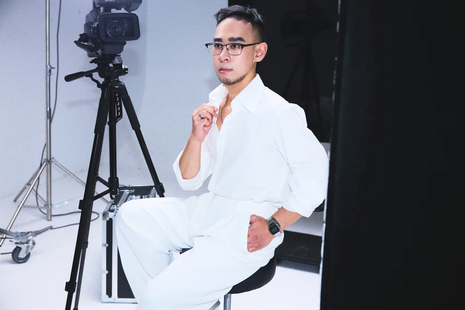 Kane seated beside a camera in a creative studio